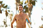 Male surfer carrying surfboard at Venice Beach, California, USA