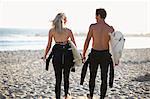 Rear view of surfing couple carrying surfboards on Venice Beach, California, USA