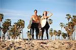 Surfing couple with surfboards looking out from Venice Beach, California, USA