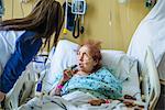 Patient on hospital bed talking to visitor