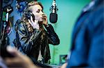 Female musician in recording studio, singing into microphone