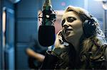 Female musician in recording studio, singing into microphone