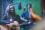 Two musicians in recording studio, playing guitar