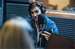 Two musicians in recording studio, wearing headphones, using microphone