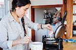 Woman in kitchen adding batter to waffle iron