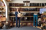 Shop assistant carrying stetsons in front of shelves of boots