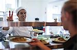 Waitress taking meal off kitchen counter for customer