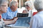 Senior man and mature women reading menu's at sidewalk cafe