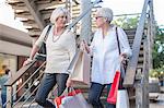 Mature women shoppers moving down shopping mall stairway