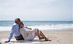 Senior couple relaxing together on beach, looking at view