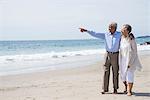 Senior couple waking together on beach, looking at view