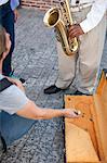 Pedestrian throwing money into street musician's music case, low section