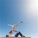 Couple practising partner yoga on bench