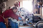 Senior men sawing woodblock on circular saw in carpentry workshop