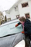 Sweden, Vastra Gotaland, Olofstorp, Man scraping ice off car windshield