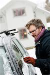 Sweden, Vastra Gotaland, Olofstorp, Man scraping ice off car window