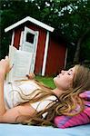 Sweden, Oland, Girl (14-15) reading book on deckchair in garden