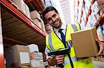Warehouse manager with yellow coat scanning barcode on box