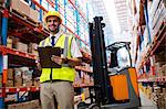 Smiling warehouse manager with clipboard