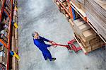 High angle view of man worker pulling the pallet truck