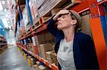 Exhausted warehouse manager`leaning on a rack