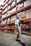 Low angle view of warehouse manager taking notes