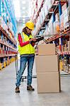 Warehouse worker standing besides cardboard box with her clipboard