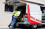 Ambulance men bringing injured people inside ambulance car