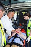 Ambulance men taking care of injured people on stretcher with doctor