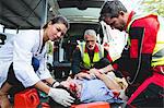 Injured man being healed by a team of ambulancemen