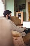 Profile view of hipster man using laptop in sofa