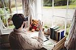 Rear view of hipster man using smart glasses while seating at desk