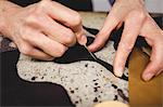 Close up of hands cutting leather