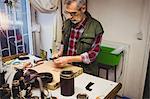 High angle view of cobbler cutting a piece of leather