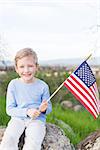 positive smiling boy holding american flag and celebrating 4th of july
