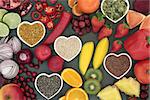 Paleo diet health and super food of fruit, vegetables, nuts and seeds in heart shaped bowls on slate background, high in vitamins, anthocyanins, antioxidants, dietary fiber and minerals.