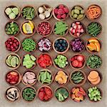 Super food sampler for paleolithic diet with fresh vegetables and fruit in wooden bowls over brown paper background. High in vitamins, antioxidants, minerals and anthocyanins.