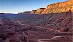 aerial view of a windy road through red sandstone canyon with coarse vegetation near Moab, Utah