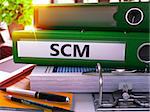 Green Office Folder with Inscription SCM - Supply Chain Management - on Office Desktop with Office Supplies and Modern Laptop. SCM Business Concept on Blurred Background. SCM - Toned Image. 3D.