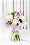Bouquet from pink tulips, violet grape hyacinths, white anemones, violet veronica and white buttercup with violet ribbon on white wooden, stylish shutter background