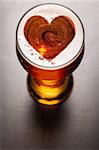 loving beer, heart symbol on foam in glass on black table, view from above