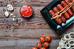 Roasted sausage in black plate on wooden table. Top view