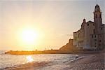 Sun rising over beach and ornate church