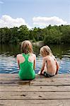 Sweden, Stockholm, Nacka, Sicklasjon, Lake Sickla, Rear view of children (6-7, 10-11) sitting on wooden jetty