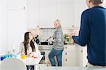 Sweden, Two women and man in domestic kitchen