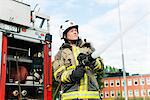 Sweden, Sodermanland, Sodertalje, Female firefighter using fire hose next to truck