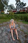 Sweden, Narke, Woman sitting on rock with digital tablet