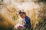 Sweden, Medelpad, Sundsvall, Juniskar, Portrait of smiling girl (4-5) sitting in field