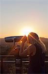 USA, California, Los Angeles, Griffith Observatory, Woman using coin-operated binoculars at sunset
