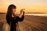 USA, California, Los Angeles, Santa Monica, Mid adult woman photographing at sunset